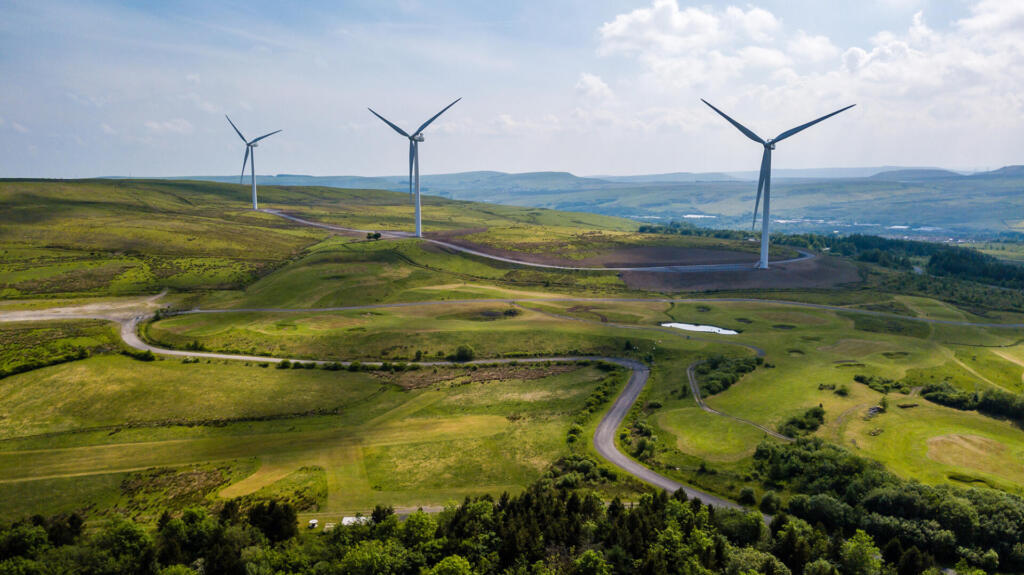 Aerial view of large wind turbines on a rural hillside in Wales